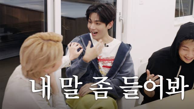 V looking surprised as Jimin reaches out to him. RM laughing aside on the right.