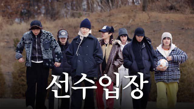 All BTS members facing forward and walking while wearing winter clothes. V on the right holding a soccer ball.